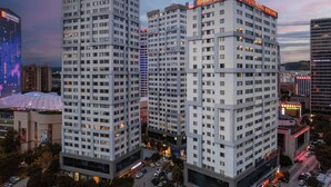 A high-rise hotel with multiple floors, a prominent sign at the top, and a surrounding urban environment with other buildings and parked cars. - Yasite Hotel Yuyuan Road Metro Station (Kunming)