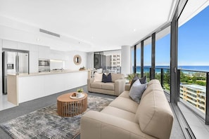A modern living space with a kitchen, a sofa, a coffee table, and a view of the ocean. - Ocean Sunrise at Oracle Level 9 (Gold Coast City)