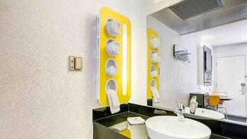 A modern bathroom with a large mirror, a white sink, and a yellow towel rack.