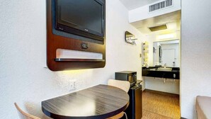 A compact room with a round table, a television mounted on the wall, a microwave, and a small seating area. - 1 Full Bed|Mobility Access Tub| NS (Thornton)