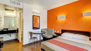 A hotel room with a bed, a desk, a chair, a small table, a mirror, and a nightstand. - 1 Full Bed|Mobility Access Tub| NS (Thornton)