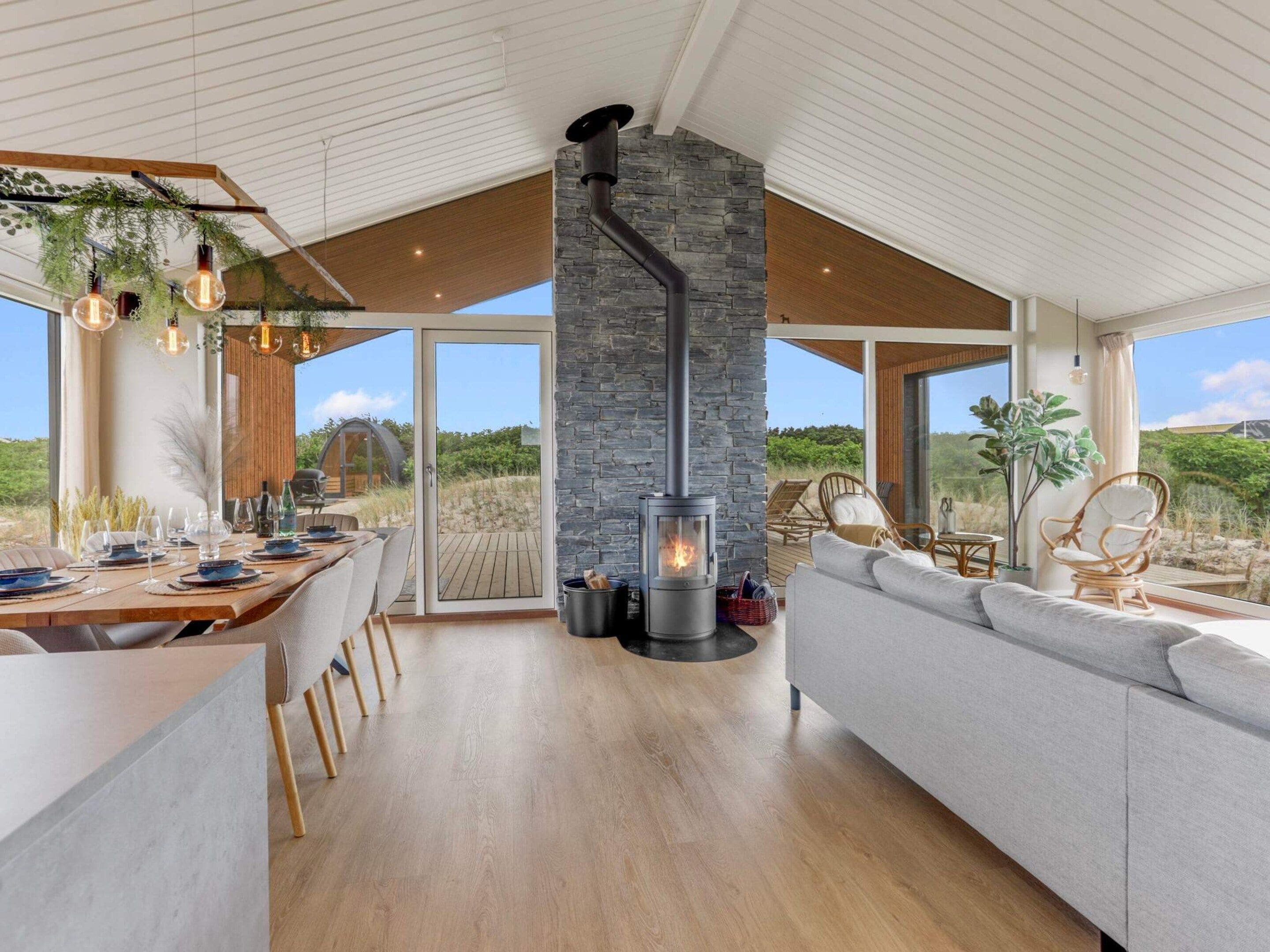 Un intérieur moderne avec une cheminée en pierre, un plancher en bois et un coin repas offrant une vue agréable.