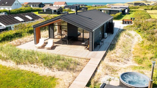 Une maison de plage moderne dotée d’une terrasse, d’un espace salon extérieur et d’un jacuzzi.