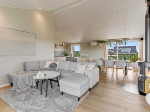 Ein geräumiges Wohnzimmer mit einem grauen Ecksofa, einem runden Couchtisch und einem Kamin.