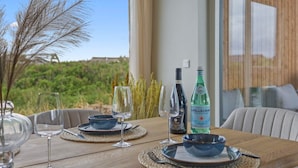 Une table à manger dressée avec des assiettes, des bols et des verres à vin, ainsi que deux bouteilles d’eau Pellegrino.