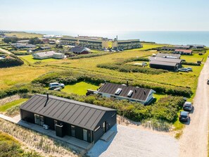 Ein Küsteneigentum mit mehreren Gebäuden, einem Sandstrand und Blick auf das Meer.