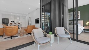 Een moderne woonkamer met een bank, twee rieten fauteuils, een salontafel en een televisie.