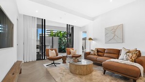 Een moderne woonkamer met een bank, fauteuil, salontafel en een zitbank.