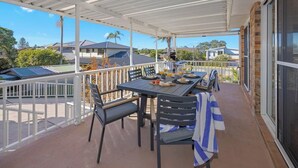 Un espace extérieur abrité, aménagé pour les repas, avec une table pour deux personnes, des chaises et un barbecue.