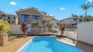 Une propriété résidentielle dotée d’une piscine, d’une maison en briques et d’une cour clôturée.