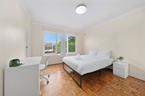 Ein Schlafzimmer mit einem Bett, Nachttischen, einem Schreibtisch und einem Fenster mit Blick.