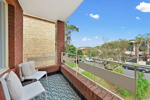 Ein Balkon mit Blick auf eine Straße, eine Backsteingemäuer und ein Fliesenboden.
