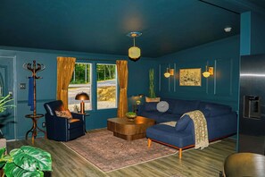 Ein salbeigrün eingerichtetes Wohnzimmer mit Sofa, Sessel, Couchtisch und einer Garderobe.