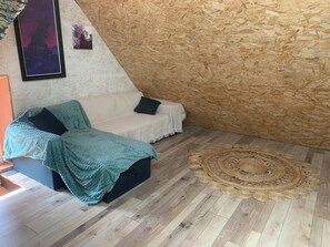 Ett mysigt rum med en vit soffa, en blå filt och en vävd matta.