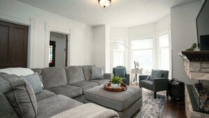 A living room with a sectional sofa, a coffee table with a plant, a fireplace, and a view of the outside. - Heated Pool and Hot Tub near Downtown Lake Geneva! (Lake Geneva)