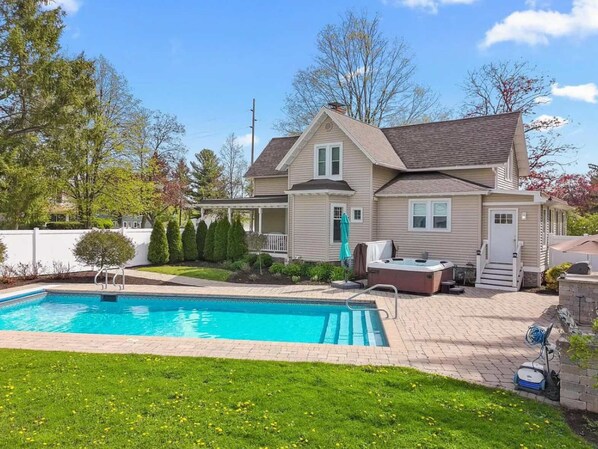 Ein zweistöckiges Haus mit Swimmingpool, überdachter Terrasse und Whirlpool.