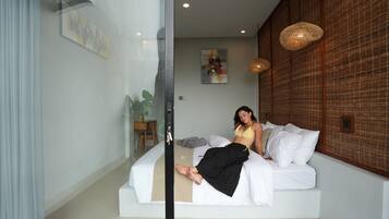 A modern bedroom with a bed, a glass partition, and a wall-mounted artwork.