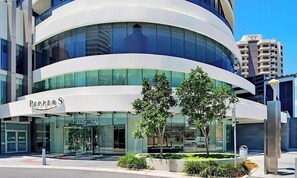 A modern building with a curved facade, large glass windows, and a sign reading 'PEPPERS.' - Luxe by the Beach at Oracle Level 13 (Gold Coast City)