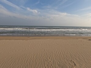 Une plage de sable fin, avec des vagues de l’océan et un ciel dégagé.
