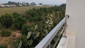 Un balcón con vista a un paisaje verde y edificios lejanos.