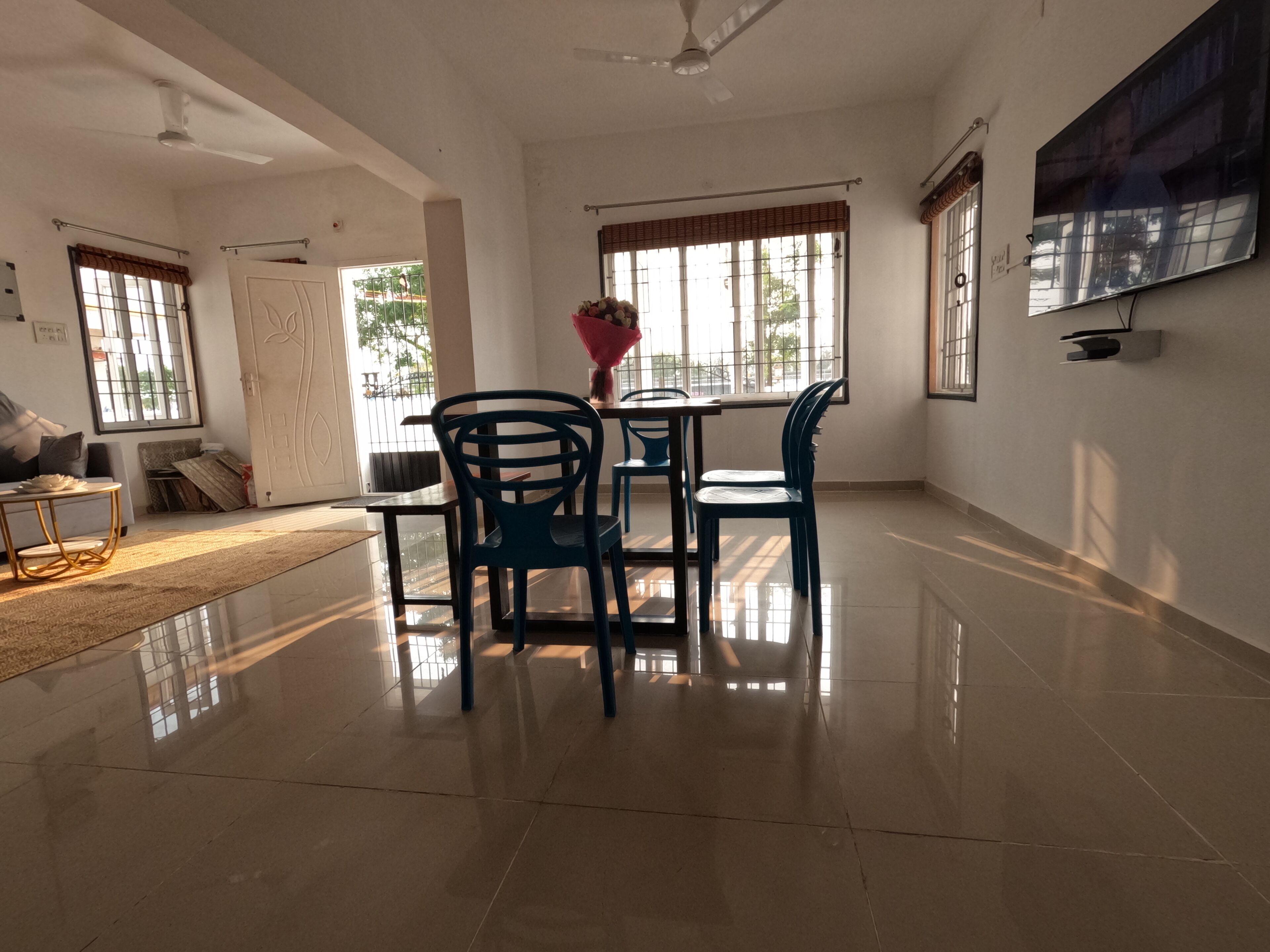 A spacious room with a dining area, a sofa, a TV, and large windows.