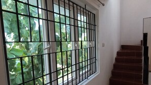 Una ventana con barrotes de metal, una escalera con escalones marrones y una pared blanca.