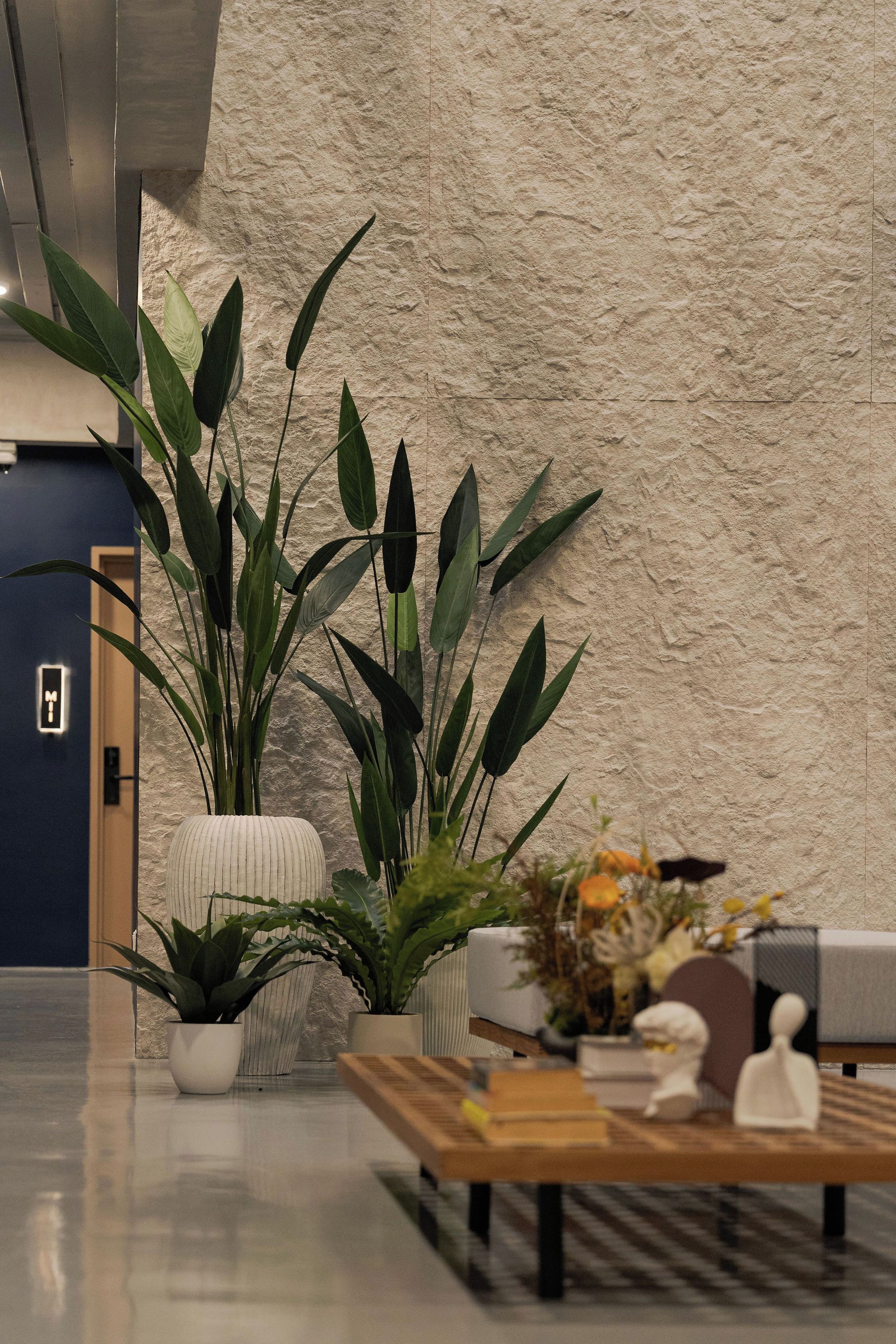 Un vestíbulo moderno con una pared texturizada, una recepción y plantas en macetas.