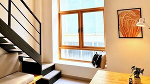 Un interior moderno con una escalera, un sofá, una mesa y un ventanal grande.