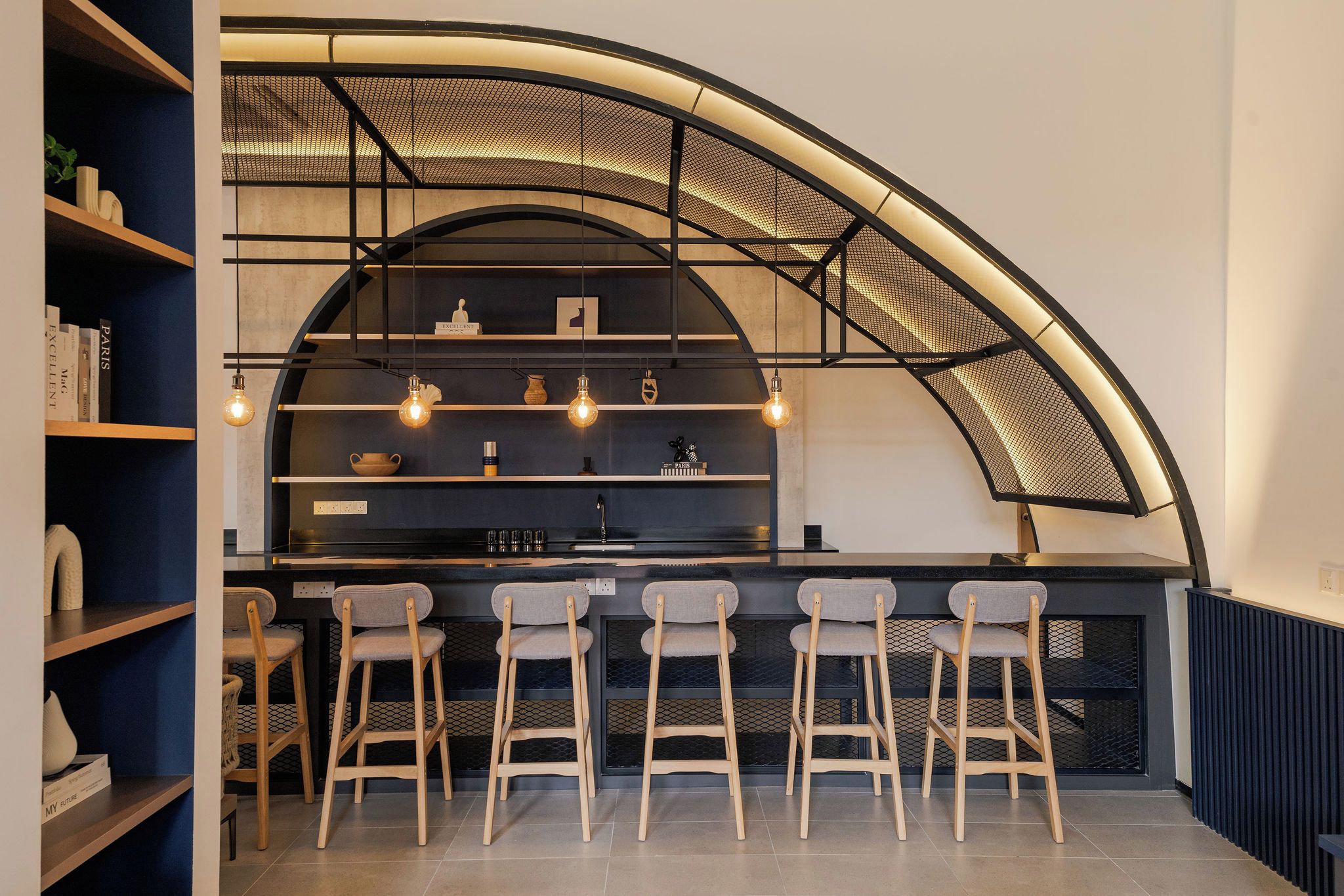 A modern kitchen with a curved ceiling, bar stools, and pendant lighting.