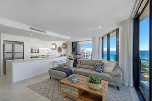 Ein modernes Wohnzimmer mit einer Couch, einem Couchtisch und Blick auf den Ozean.
