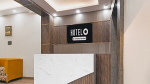 A hotel reception desk with a 'HOTELO Company-Serviced' sign, wooden paneling, and a marble counter. - Hotel O Jamshedpur Near Burma Mines (Golmuri)