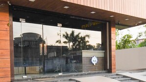 A modern building entrance with glass doors, a ramp, and a logo on the wall. - Hotel O Jamshedpur Near Burma Mines (Golmuri)