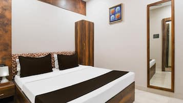A bedroom with a bed, bedside table, nightstand, wardrobe, mirror, and a wall-mounted artwork.