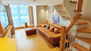 A modern living room with a sofa, ottoman, and a staircase. - Kunming Fish Inn City Center Nanping Street Branch (Kunming)