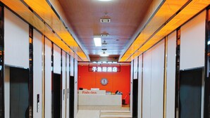 A hotel corridor with a reception desk labeled 'Fish-Inn,' featuring a red wall and a wooden ceiling. - Kunming Fish Inn City Center Nanping Street Branch (Kunming)