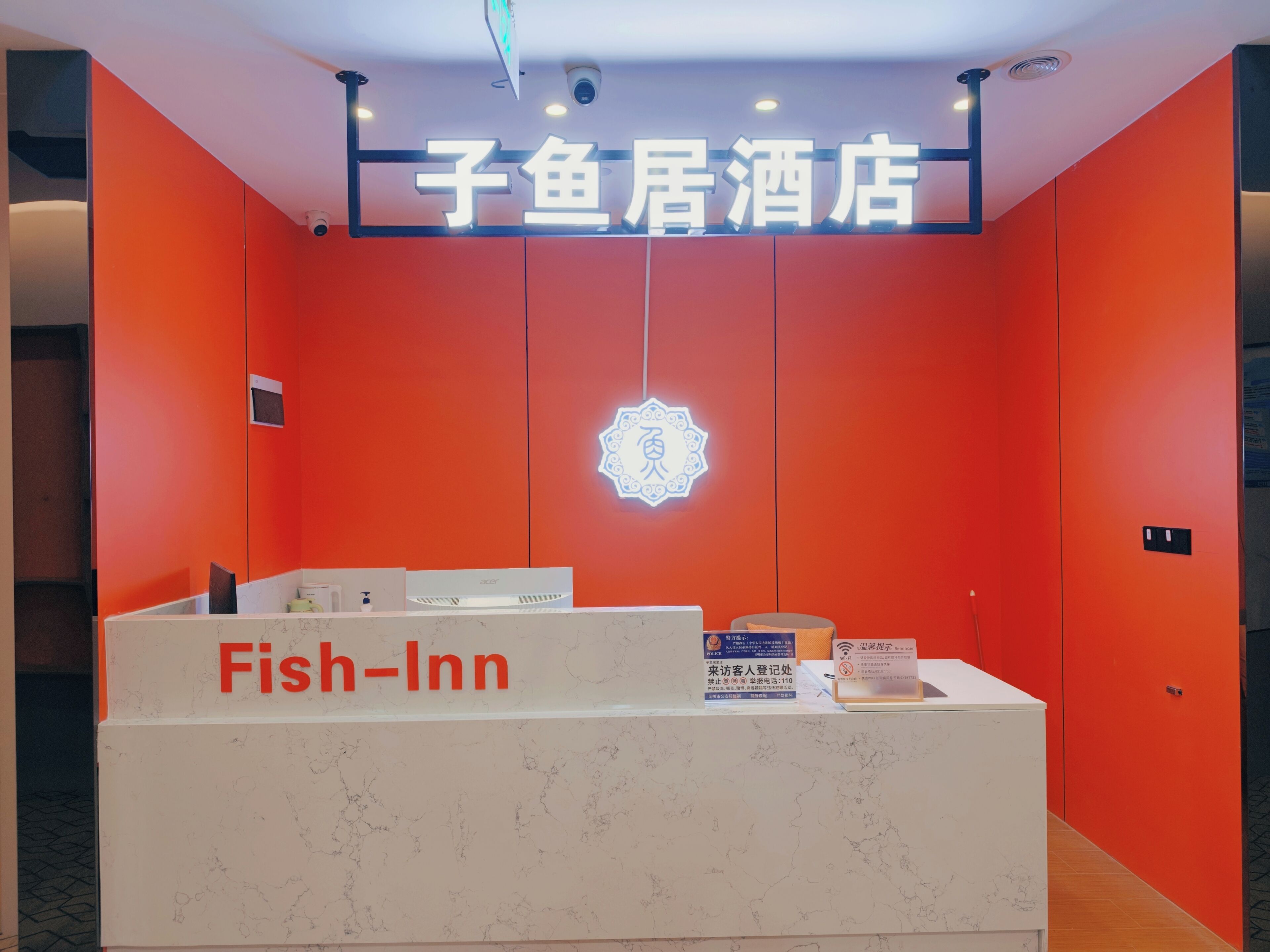 A reception desk with a sign reading 'Fish-Inn' and a neon sign above it.