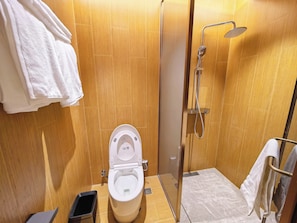 Une petite salle de bain comprenant des toilettes, une douche et un porte-serviettes.