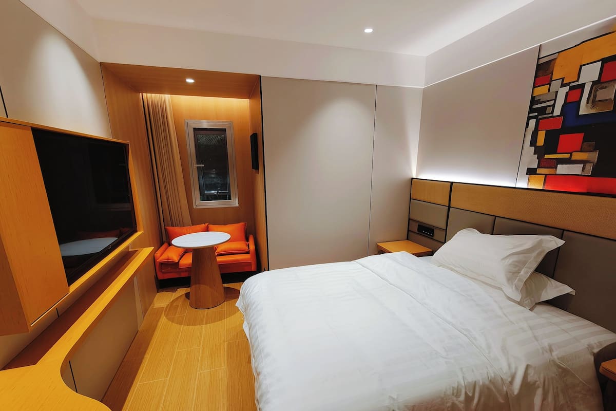 A hotel room with a bed, a TV, a sofa, and a small table.