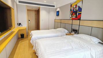 Camera d'albergo con due letti, televisione, macchina del caffè e un quadro appeso al muro.