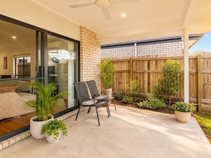A covered patio with a seating area, potted plants, and a wooden fence. - Spacious 4B Near Logan with Parking (Logan Reserve)