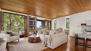 Un espacio habitable amplio con techo de madera, ventanas grandes y vistas al exterior.