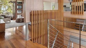 Un interior moderno con una escalera, paneles de madera y vistas al exterior.