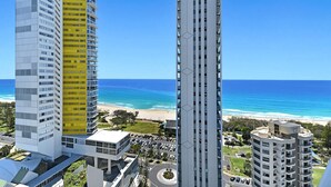 Ein Hochhaus-Hotel mit mehreren Stockwerken, einem Parkplatz und Blick auf den Strand.