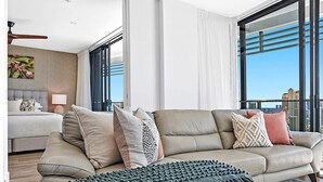 Ein modernes Wohnzimmer mit einer Couch, Kissen, einer Decke, einem Beistelltisch und einer Lampe.