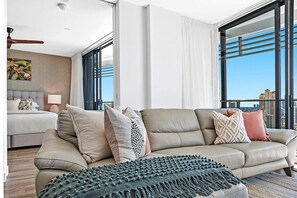 A modern living room with a sofa, pillows, a throw blanket, a side table, and a lamp. - Beach Sunrise at Oracle Level 21 (Gold Coast City)