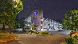 Un hôtel reconnaissable à son grand panneau indiquant le chiffre « 6 », doté d’un parking et d’un aménagement paysager bien entretenu.