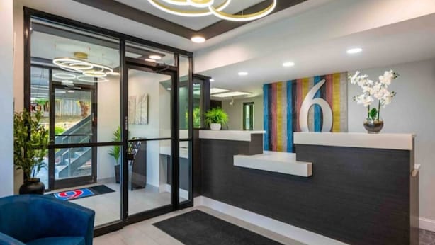 Un espace d’accueil doté d’une porte d’entrée en verre, d’un comptoir de réception et d’une chaise bleue.