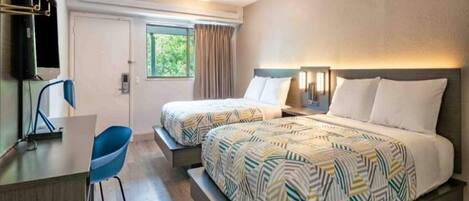 Habitación de hotel con dos camas, un escritorio y una silla.