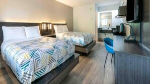 Une chambre d’hôtel avec deux lits, un bureau, une chaise et un téléviseur.