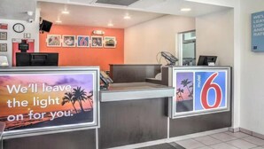 Bancada de recepção de hotel com um aviso que diz 'Deixaremos a luz acesa para você'.